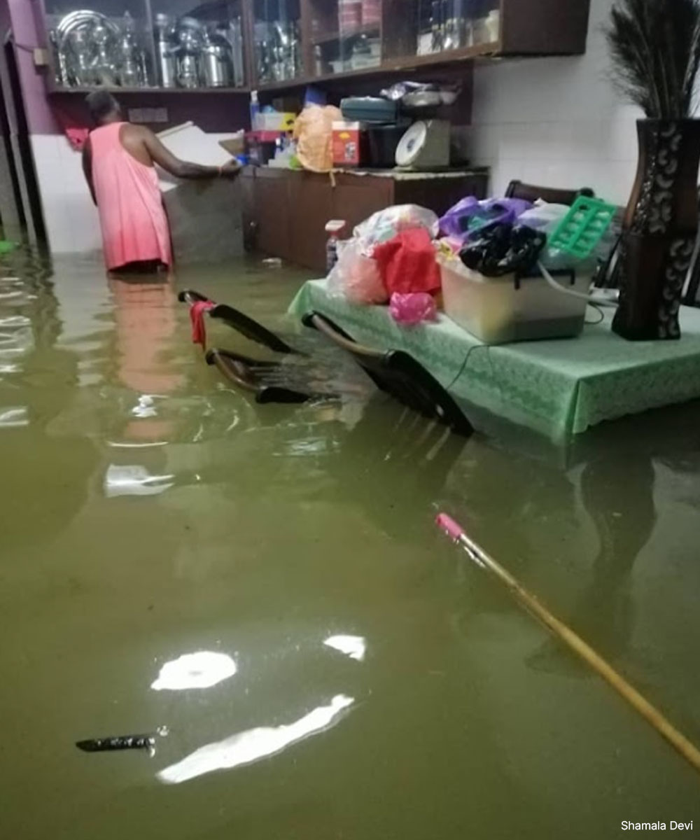 Suami Shamala Devi menolak peti ais yang dibawa air banjir, di dalam rumah mereka pada Disember, 2021. Gambar oleh Shamala Devi.