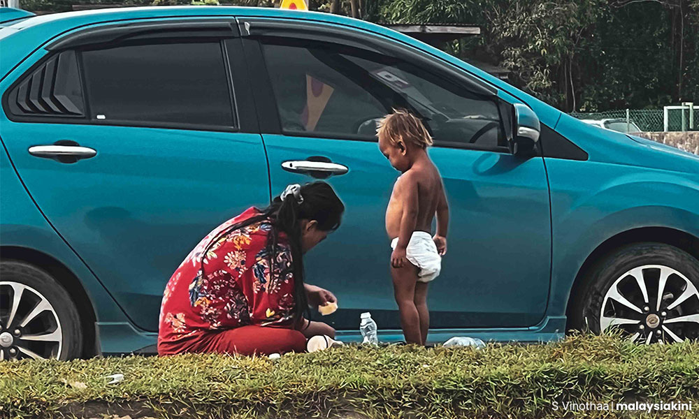 A woman making a bottle of milk for her child on a road divider.