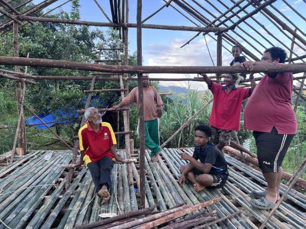 Azlan Ahak, 19, (duduk, kanan), bersama bapanya, Ahak Uda, 57, (duduk, kiri) dan lain-lain penduduk berehat sebentar semasa membina sebuah rumah.